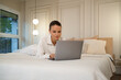 © ADDICTIVE STOCK - Young woman working on laptop in cozy bedroom setting