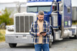 © be free - Hispanic trucker at truck. Using tablet chatting with customer. Service diagnostics for truck. Man use tablet to configure equipment. Trucker driver man with tablet control loading. Truck maintenance
