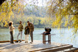 © BGStock72 - Friends enjoying a sunny day by the water with a barbecue grill nearby