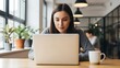 © Lucas - A young woman working on her laptop in a modern office space with plants and natural light work, coworking, study