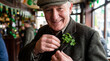 © Creative mind - An elderly Irish man smiling and holding a shamrock in a cozy pub