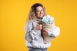 © New Africa - Happy woman with bag full of money showing thumbs up on yellow background