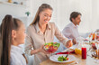 © Prostock-studio - Young woman putting vegetable salad on her daughter's plate during festive family dinner at home. Little girl celebrating holiday with her parents, having tasty meal together