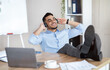 © Prostock-studio - Taking break from work. Smiling Arab man listening to music in headphones, relaxing at workplace. Happy millennial guy sitting at table with laptop and enjoying his favorite song