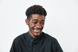 © SHOTPRIME STUDIO - Young black man with dark skin and curly hair smiling and looking down wearing black shirt on white background. Portrait of happy African ethnicity male with casual style.