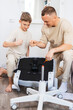 © Aboltin - Young father teaching son how to assemble furniture at home. Parenting moment, teamwork, child development, indoor family activity and modern lifestyle concept. Fathers day.