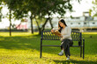 © Wasana - Young woman reading book on park bench relaxing