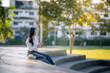 © Wasana - Young woman sitting in park using smartphone