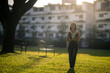 © Wasana - Woman student walking in park with books at sunset