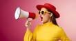 © rdkcho - Stylish woman in yellow shirt and red hat yelling into a megaphone for an announcement or promotion.
