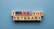 © julijadmi - Wooden blocks spelling out 'THANK YOU VETERANS' with an American flag design on a blue background for patriotic recognition and appreciation