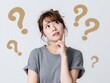 © Jumpei - 疑問符に囲まれ考え込む表情を見せる若い女性の悩みシーン