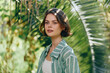 © SHOTPRIME STUDIO - Portrait of a young woman outdoors among lush greenery, wearing a striped green shirt, soft natural light and calm expression.