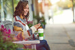 © peopleimages.com - Coffee, happy and woman on bench with phone, post reaction and communication on chat site. Space, technology and female person in town with cup, app update and online message on social media.