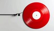 © bento - Red vinyl record with white label resting on a light gray surface.