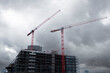 © yaqui_villegas - Construction crane highrise building skyline architecture development engineering cloudy progress with dramatic weather over modern city