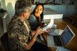 © Marko Geber - Couple reviewing bills and finances at home kitchen table