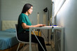 © AntonioDiaz - Profile view of a woman performing remote work, connecting online with laptop and keyboard from her comfortable home office