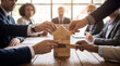 © David Zarzosa - Business team building house model from wooden blocks in meeting, concept of teamwork, real estate planning, mortgage, insurance and investment strategy.