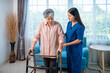 © wirojsid - Senior Asian woman with walker receiving caregiver assistance at home