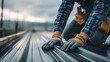 © Marvel’s Nook - Roofing metal installation with worker wearing gloves handling metal sheet panels on roof, representing construction, craftsmanship, and durable roofing solutions