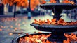 © HarStock - An ornate empty fountain in a public plaza filled with fallen autumn leaves and flowing water