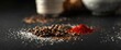 © TheWaterMeloonProjec - assorted salt, peppercorns, and red spice scattered on black background