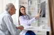 © Anastasiya - Female doctor holding medical scan and pointing details while consulting senior male patient, diagnostic imaging and healthcare consultation concept