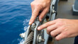© Iryna - Caucasian sailor hands checking metal cable fastening on ship deck, marine safety and equipment maintenance