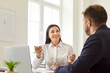© Studio Romantic - Professional financial advisor talking to a client. Happy smiling friendly young brunette woman in a white shirt sitting at an office desk, communicating with a male customer, offering a business deal