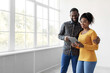 © Prostock-studio - Smiling young african american husband and wife looking in tablet, choosing interior for home, standing near window in living room. Renovation, relocation, moving, design app and modern technology