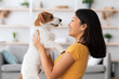 © Prostock-studio - Emotional young asian woman petting her cute dog at home, loving korean lady playing with fluffy jack russel terrier in living room, closeup portrait. People and dogs, pets adoption concept