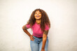 © Paula - Laughing African American woman in pink shirt bending forward playfully against wall