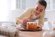 © New Africa - Young woman decorating traditional Easter cake with sprinkles in kitchen