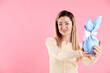 © New Africa - Easter celebration. Smiling woman holding wrapped gift on pink background, space for text