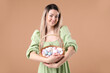 © New Africa - Easter celebration. Smiling woman in dress with wicker basket full of painted eggs on beige background