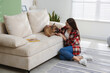 © New Africa - Woman with her cute dog near sofa at home
