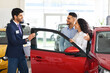 © Prostock-studio - Millennial muslim man and woman couple customers choosing new family car in showroom, standing by luxury red auto and listening to cheerful young sales assistant in stylish suit, side view
