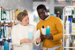 © JackF - Couple adult man and woman buyers chooses shampoo or shower gel and body washcloth in household chemicals store