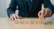© SULTAN - Businessman rating customer satisfaction with wooden blocks in neutral office lighting for corporate feedback