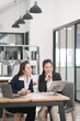 © Thitisak - Asian businesswoman sitting at work using laptop talking and consulting in office