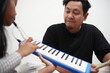 © airdone - Asian father teaching his young daughter how to play the melodica and recorder at home