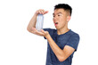 © fotolite - An Asian teenager holding up and examining an empty plastic water bottle against a white background, ideal for water conservation, recycling, or environmental awareness concepts.
