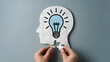 © Muhammad Tahir Khan - Hands placing puzzle piece into head with lightbulb idea on gray background symbolizing insight and problem solving