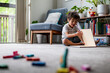 © NZstockphoto - A young boy sits on the floor with a book, surrounded by colourful toys and plants