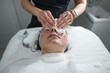 © Gonzalo Infiesta - Esthetician cleansing woman's face during skin care treatment