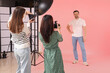 © Pixel-Shot - Female photographers taking pictures of man during master class in studio, back view