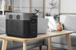 © Pixel-Shot - Portable power station with laptop on table in living room, closeup