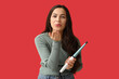 © Pixel-Shot - Beautiful young woman with curling iron blowing kiss on red background