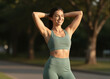 © Yannick - Smiling woman in sage green activewear stretching outdoors